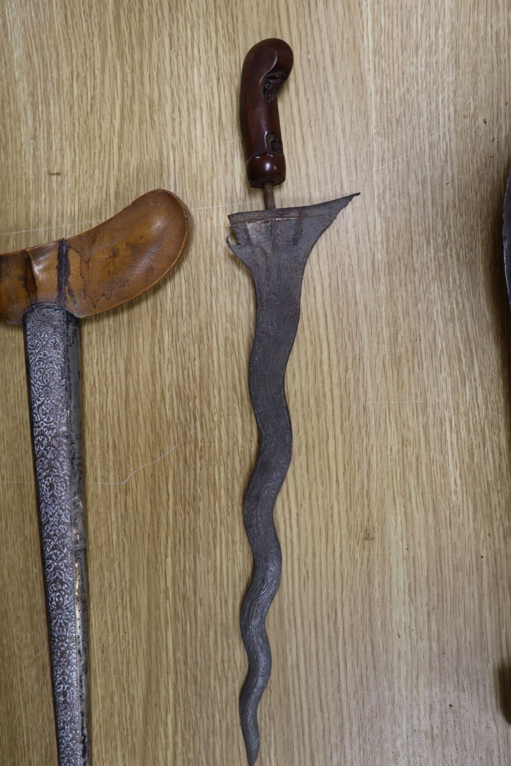 A 19th century Javanese kris, with 14 inch blade, two other edged weapons and a ceremonial head-dress